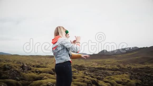 两名女游客站在冰岛的熔岩上手指着什么快乐的女人说话视频的预览图