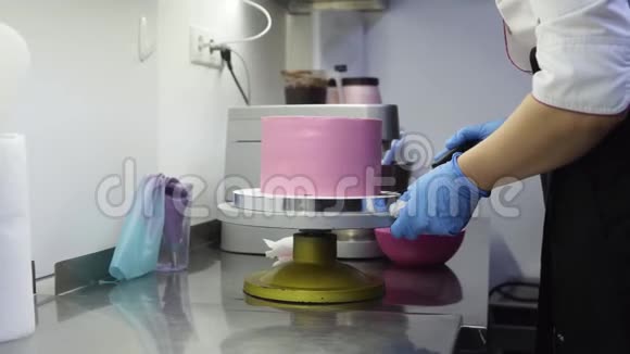 在特殊的托盘上旋转一个紫色蛋糕同时完成装饰它把多余的鲜奶油放在底部视频的预览图