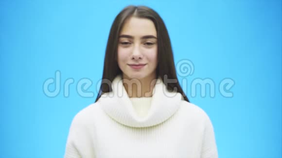 一位穿着白色温暖毛衣的快乐年轻女人的肖像在这段时间里一个手势显示和感觉视频的预览图