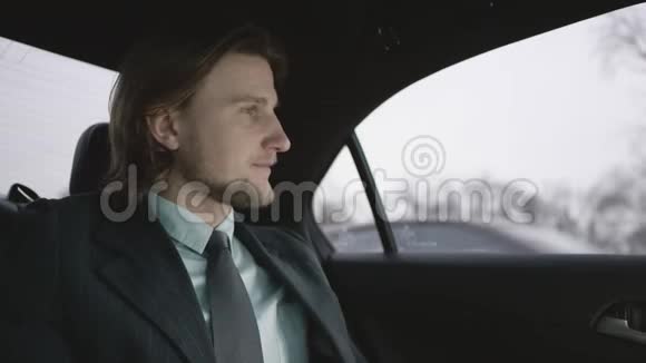 一个棕色头发的人穿着开心果衬衫穿着灰色西装坐在车里然后付钱视频的预览图