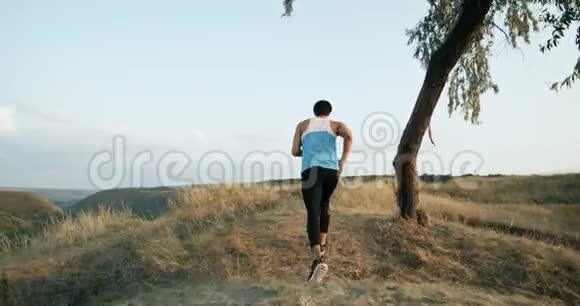 一个穿着运动服的年轻人在山上用绳子锻炼耐力在大自然中揉捏视频的预览图