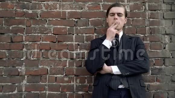 一个穿着20世纪20年代西装的人靠在墙上神情忧郁地抽烟视频的预览图
