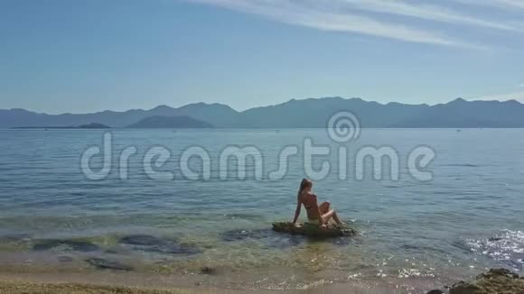 镜头移近石头上的女孩在拍打海水视频的预览图