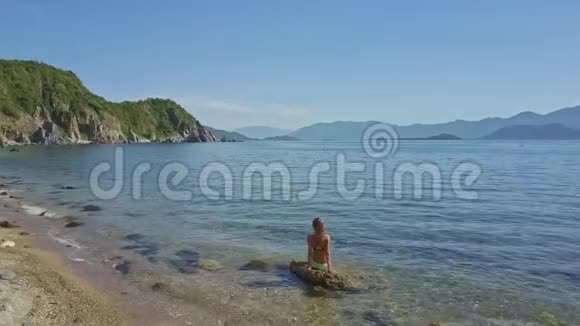 海洋中的石头上的钻景女孩与山丘天际线视频的预览图