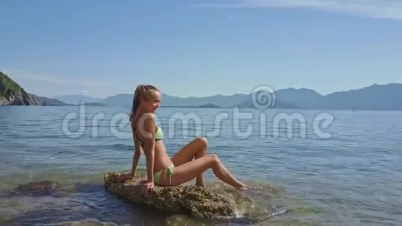 在浅海水中的岩石上绕着女孩向天空飞去视频的预览图