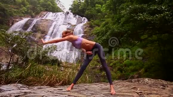 光着脚的金发女孩在瀑布里做瑜伽姿势视频的预览图