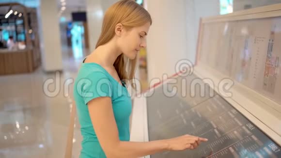 美丽的年轻女子穿着绿松石T恤在商场在商场布局上寻找特定的商店视频的预览图