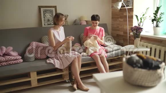 微笑的女性朋友在家里的工作间的沙发和编织针上聊天视频的预览图
