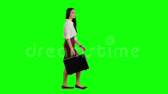 亚洲女孩看着路上手里拿着一个公文包绿色屏幕视频的预览图
