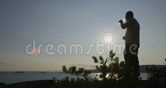 活跃的徒步旅行者在日落时在海边休息和喝水视频的预览图