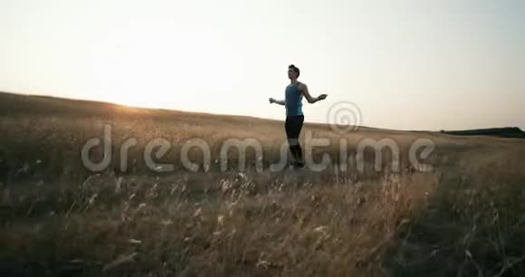 一个穿着运动服的年轻人在山上用绳子锻炼耐力在大自然中揉捏视频的预览图