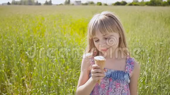 一个漂亮的金发女孩夏天在麦田旁边吃冰淇淋跑到远处温暖阳光视频的预览图