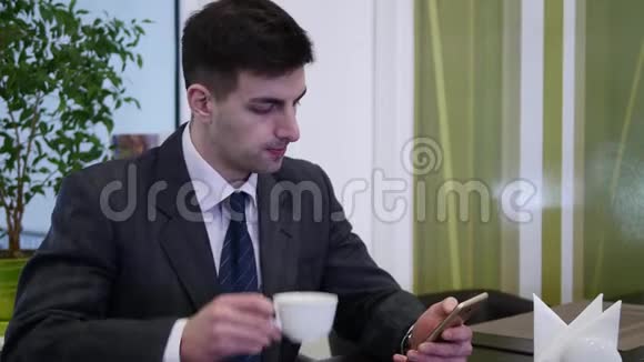 一个男人坐在咖啡馆的桌子旁用电话他左手的电话视频的预览图