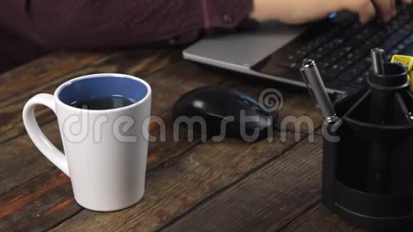 特写杯子里的饮料用电脑鼠标和笔记本电脑键盘工作视频的预览图