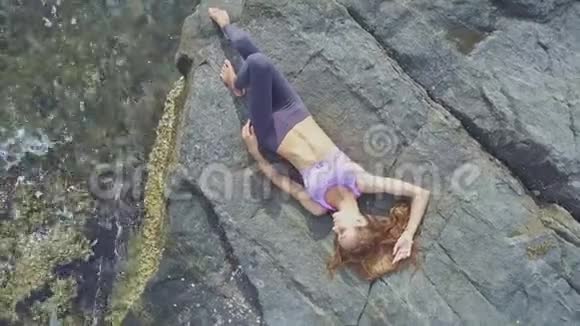鸟瞰女孩躺在岩石海滩与绿松石的海洋视频的预览图