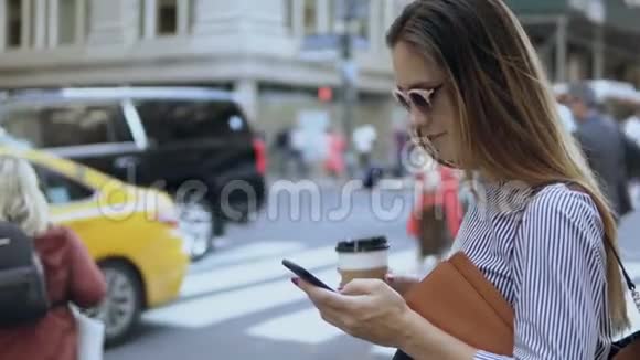 年轻漂亮的女商人在交通路附近使用智能手机女性拿着文件和咖啡杯视频的预览图