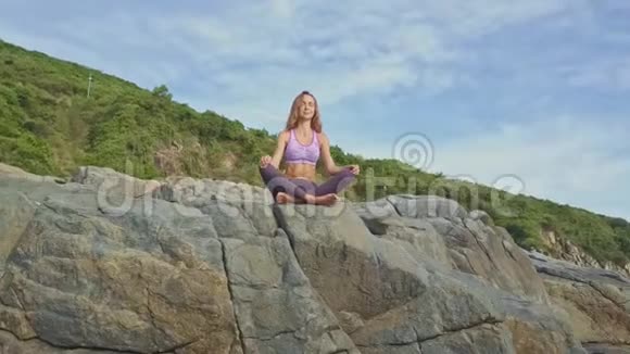 在岩石边缘坐着瑜伽姿势的女孩身上坐着一个机器人视频的预览图