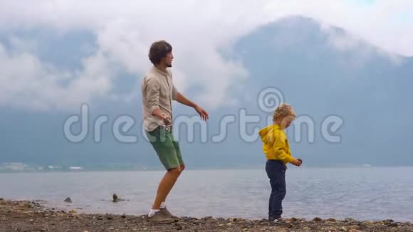 一对父子向印度尼西亚巴厘岛高地的布拉坦湖投掷石块的慢镜头视频的预览图