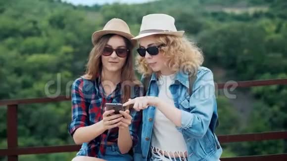 两位在山上的女性旅行者在徒步旅行中讨论和看智能手机视频的预览图