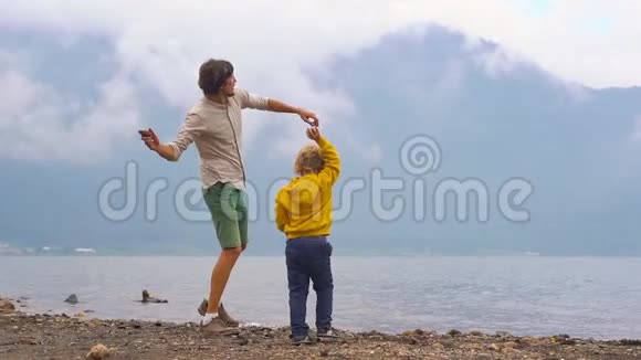 一对父子向印度尼西亚巴厘岛高地的布拉坦湖投掷石块的慢镜头视频的预览图