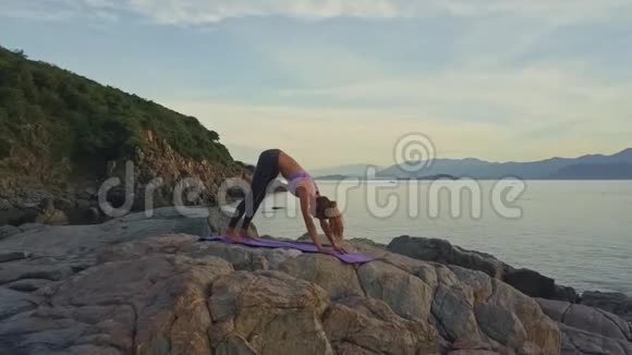 侧景女孩在海滩上做瑜伽姿势对抗太阳升起视频的预览图