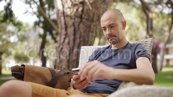 男人在智能手机上发短信在街头咖啡馆喝咖啡视频的预览图