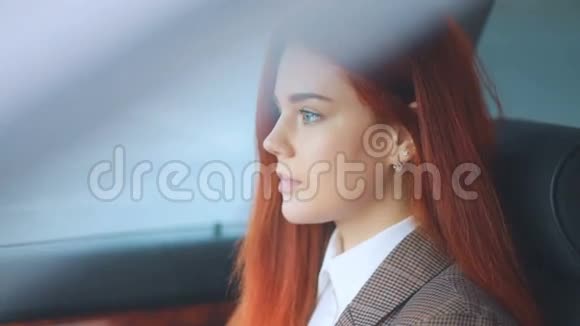 红发美女模特红发女郎身穿棕色夹克和白色t恤深蓝色眼睛坐在车里视频的预览图
