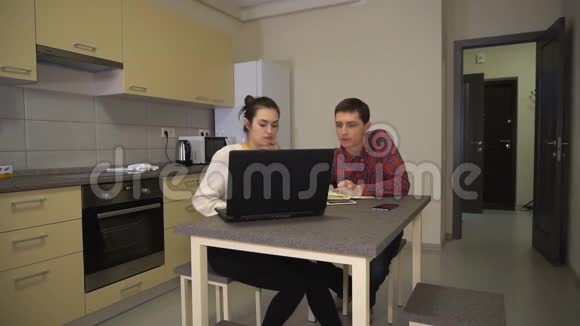 他教女孩坐在厨房里用笔记本电脑视频的预览图