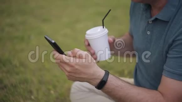 男人坐在草坪上喝咖啡打电话视频的预览图