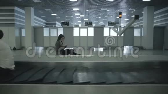 坐在机场移动行李带上的成年人视频的预览图