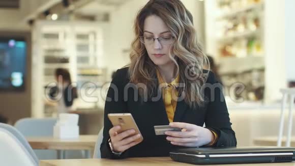 一个穿着西装的女孩用智能手机用信用卡付款视频的预览图