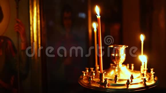在宗教圣像背景上点燃蜡烛的烛台视频的预览图