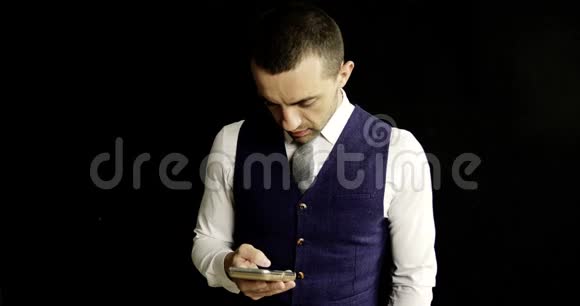 一个年轻的商人穿着白色衬衫和蓝色背心使用手机视频的预览图