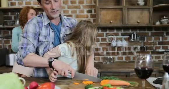孩子在厨房帮父母做饭幸福的母亲看着父亲和两个孩子在家准备食物视频的预览图