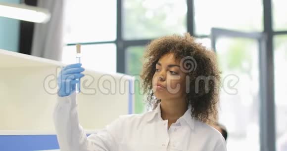 非裔美国科学家女性研究试管中的化学物质与实验室同事讨论实验视频的预览图