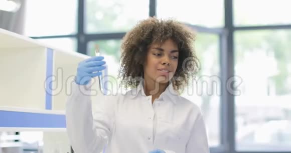 非裔美国科学家女性研究试管中的化学物质向研究人员展示与团队的实验视频的预览图