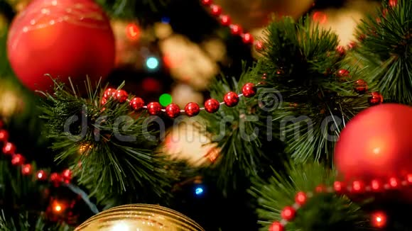 特写4k片红色和金色的子挂在圣诞树上闪烁着五颜六色的灯光视频的预览图