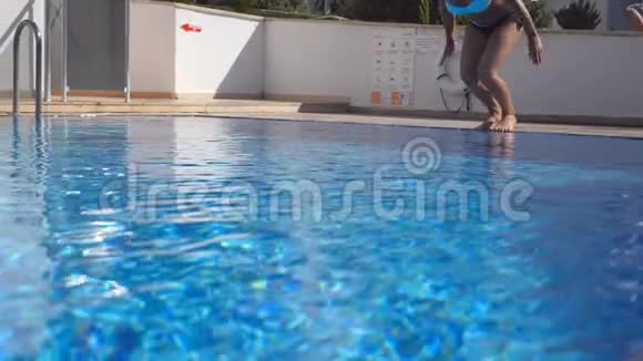 阳光明媚的日子年轻漂亮的女人在盆水里跳布鲁内特女孩在游泳池游泳并在晴天放松视频的预览图