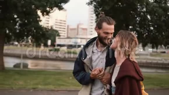 年轻的幸福夫妇一起在公园里散步美丽的男人和女人牵着手在日落时玩得很开心视频的预览图
