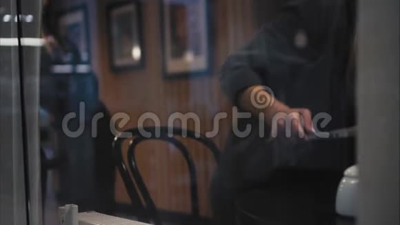 一个时髦的时髦女人坐在咖啡馆里找一张桌子打开笔记本电脑开始工作从窗口观看视频的预览图