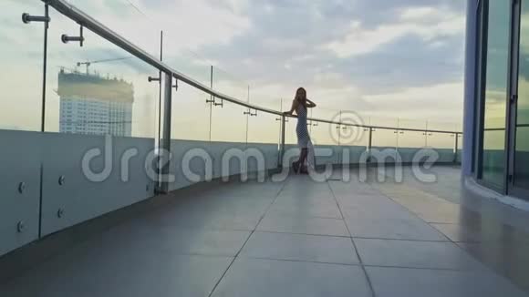 站在酒店阳台上与摩天大楼对抗的女孩动议视频的预览图