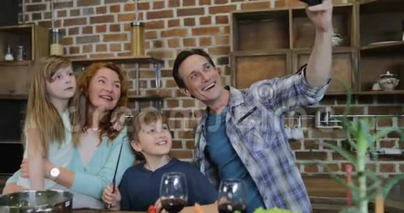 快乐家庭在厨房做饭时拍照父母和孩子在家准备食物视频的预览图