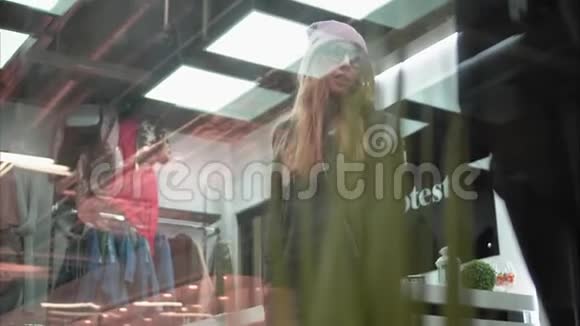 一个时髦的时髦女人在商店里试穿时髦的工作服通过窗口查看购物视频的预览图