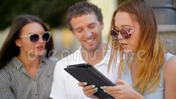 一群带着平板电脑的学生穿着淡蓝色裙子的女孩正在读一些东西她的女性朋友和视频的预览图
