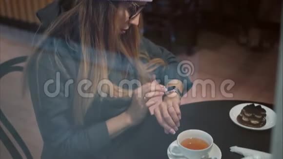 一位戴着眼镜戴着智能手表打着电话在咖啡馆喝咖啡的时髦时髦女视频的预览图