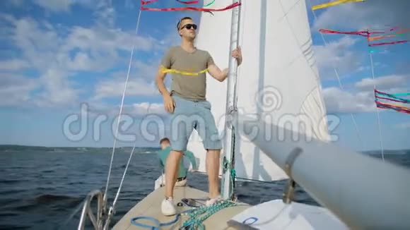 这艘游艇的船长是一位英俊的年轻人他在夏天拉着绳子在海里航行视频的预览图