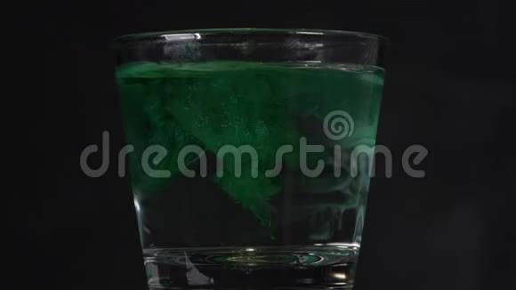 绿色墨水被溶解在一杯水中并创造了抽象的背景视频的预览图