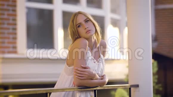 一个年轻而浪漫的女人的肖像她叠着头发站在一个开放的阳台上在一个夏天和温暖的日子里视频的预览图