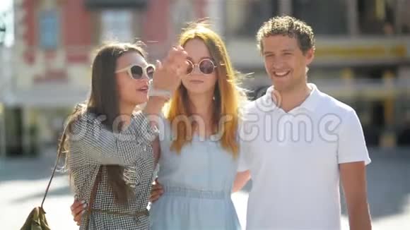 一个英俊的男人和两个迷人的年轻女孩在旧城广场聊天和微笑在一起的时间视频的预览图