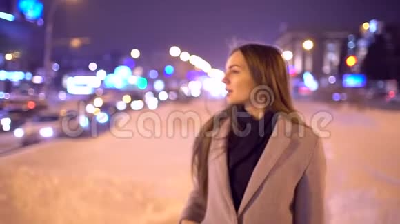 街边城市年轻美女画像年轻美丽的女人在城市的夜晚漫步微笑视频的预览图